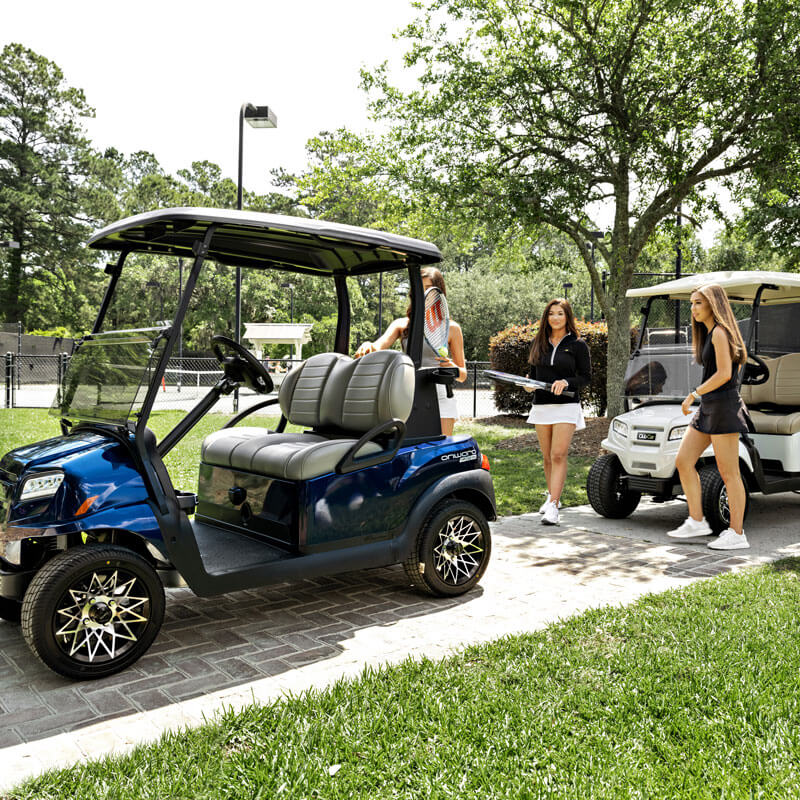A golf cart is parked on a paved path with people nearby in Nassau, Bahamas